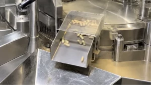 Finished capsules moving down a capsule filling machine chute